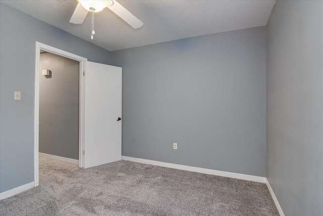 spare room featuring light carpet, ceiling fan, and a textured ceiling