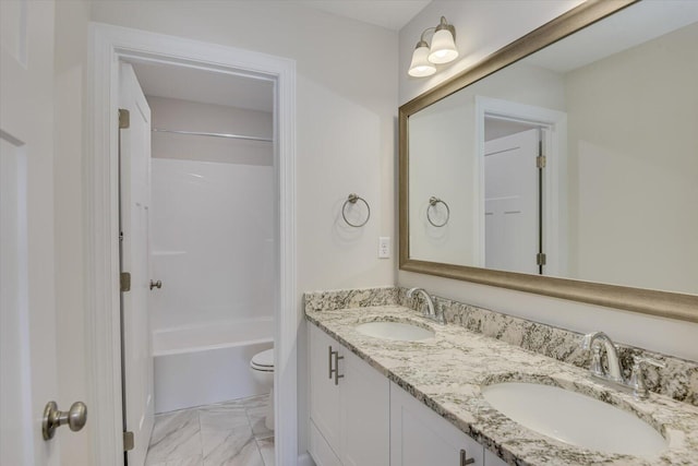 bathroom with double vanity, marble finish floor, toilet, and a sink