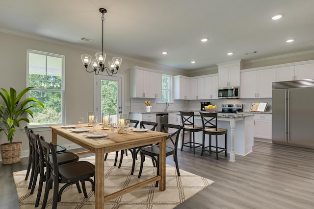 dining area featuring ornamental molding, a healthy amount of sunlight, visible vents, and light wood finished floors