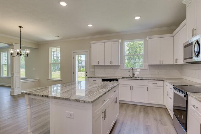 kitchen featuring a center island, white cabinets, sink, black range with electric cooktop, and a chandelier