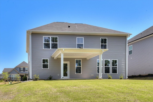 rear view of house featuring a shingled roof and a lawn