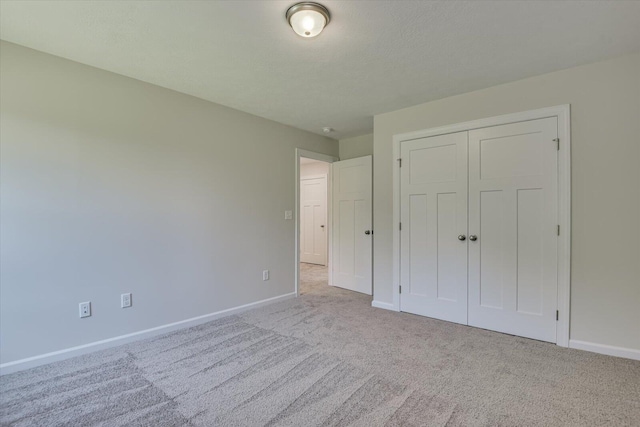 unfurnished bedroom with light carpet and a closet