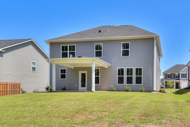 rear view of property featuring a yard and fence