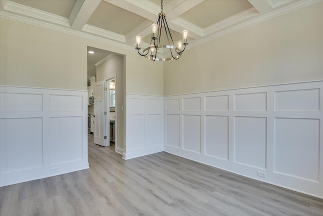 unfurnished dining area featuring light wood finished floors, a chandelier, a decorative wall, and beam ceiling