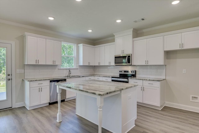 kitchen with light stone countertops, appliances with stainless steel finishes, tasteful backsplash, white cabinets, and a center island