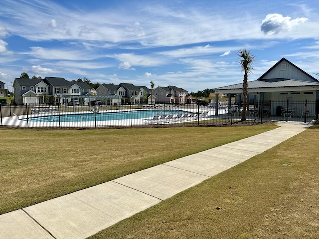 community pool with a residential view, a yard, and fence