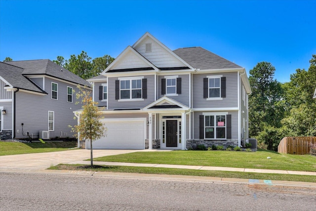 craftsman-style home with concrete driveway, a front yard, fence, a garage, and stone siding