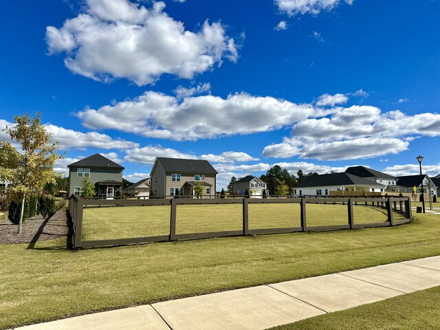 view of community with a residential view, fence, and a lawn