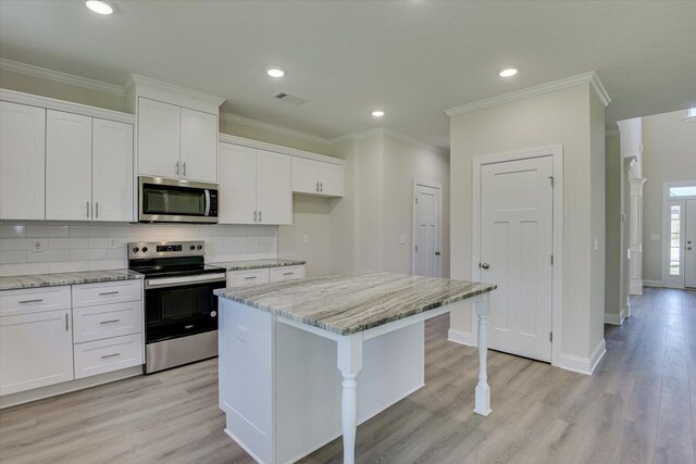 kitchen with white cabinets, a kitchen island, light stone counters, and stainless steel appliances