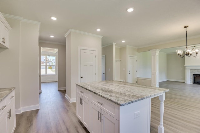 kitchen with a breakfast bar, a notable chandelier, a fireplace, light wood-style floors, and white cabinets