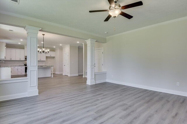 unfurnished living room featuring ceiling fan with notable chandelier, light wood-type flooring, and ornamental molding