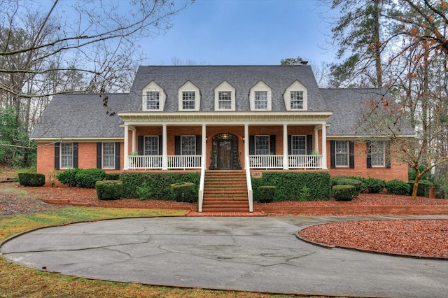 cape cod-style house featuring covered porch