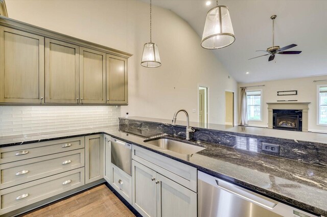 kitchen with pendant lighting, dishwasher, dark stone counters, sink, and tasteful backsplash