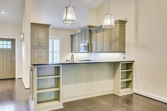 kitchen with kitchen peninsula, decorative backsplash, dark wood-type flooring, sink, and hanging light fixtures