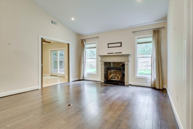 unfurnished living room with a healthy amount of sunlight, vaulted ceiling, and light hardwood / wood-style floors