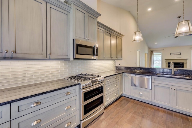 kitchen with tasteful backsplash, stainless steel appliances, sink, pendant lighting, and gray cabinets