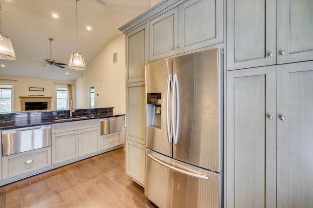 kitchen featuring gray cabinetry, sink, hanging light fixtures, stainless steel fridge with ice dispenser, and vaulted ceiling