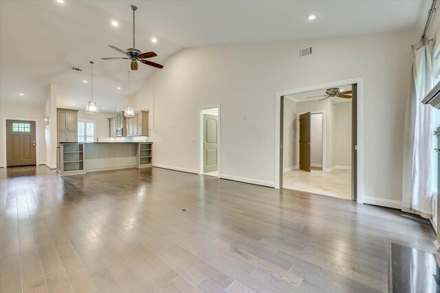 unfurnished living room with hardwood / wood-style floors, high vaulted ceiling, and ceiling fan