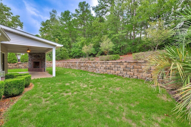 view of yard with ceiling fan, a patio, and an outdoor brick fireplace