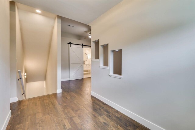 hallway with a barn door and dark hardwood / wood-style flooring