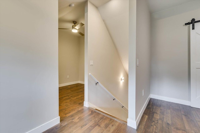 stairway featuring a barn door, hardwood / wood-style flooring, and ceiling fan