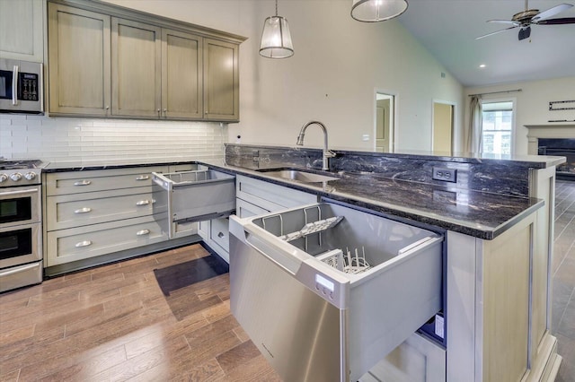 kitchen with sink, backsplash, pendant lighting, lofted ceiling, and appliances with stainless steel finishes