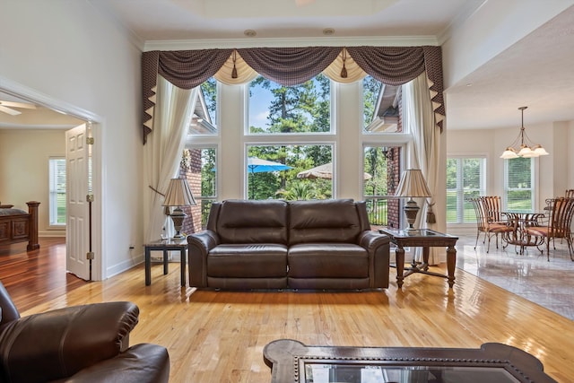 living room featuring ceiling fan with notable chandelier, light hardwood / wood-style flooring, and ornamental molding