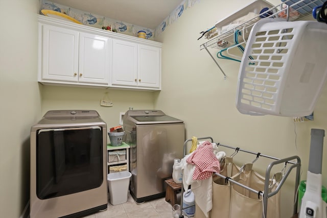 laundry area featuring cabinets, light tile patterned flooring, and washing machine and clothes dryer