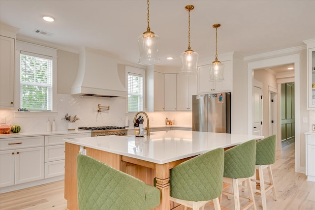 kitchen featuring light countertops, appliances with stainless steel finishes, a healthy amount of sunlight, and premium range hood