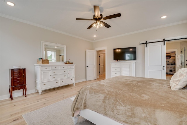 bedroom with a barn door, ornamental molding, baseboards, and light wood finished floors
