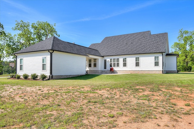 back of house with a yard and a shingled roof
