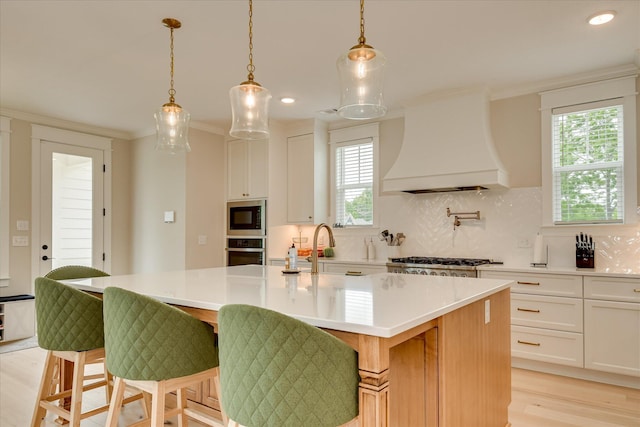kitchen with premium range hood, plenty of natural light, light wood-style flooring, and appliances with stainless steel finishes