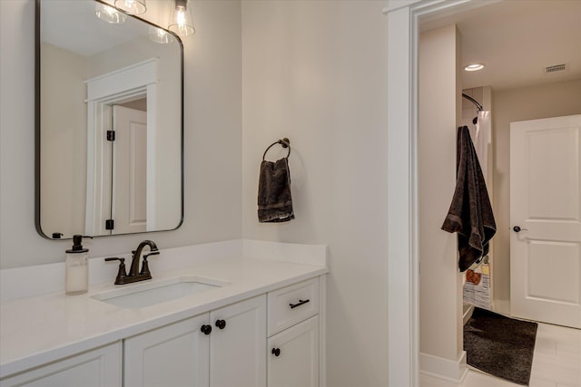 bathroom with visible vents, a shower, and vanity