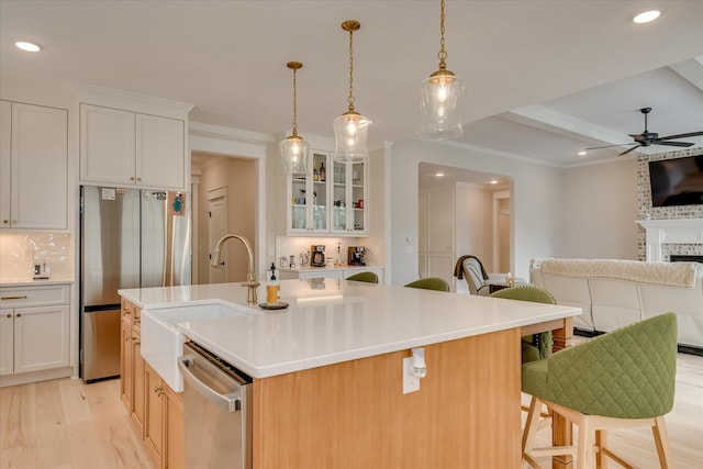 kitchen featuring open floor plan, ceiling fan, a sink, light wood-style flooring, and stainless steel appliances