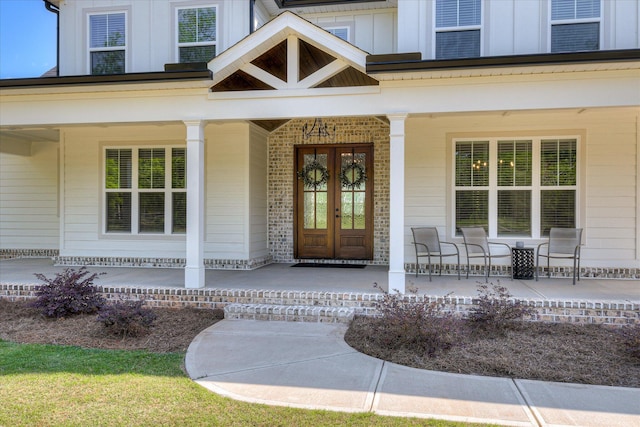 entrance to property with covered porch, board and batten siding, and brick siding
