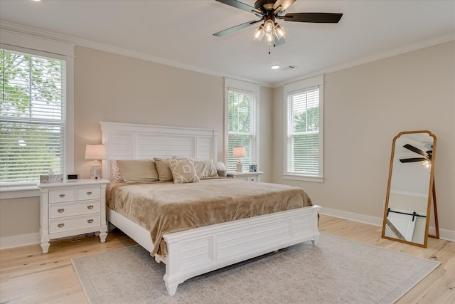 bedroom featuring ornamental molding, light wood-style flooring, and multiple windows