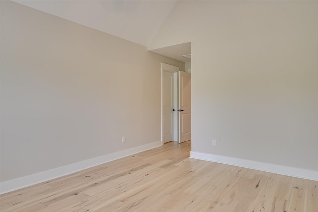 spare room featuring baseboards, light wood finished floors, and high vaulted ceiling
