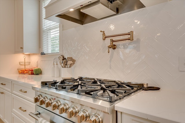 details featuring backsplash, white cabinetry, high end stainless steel range, and wall chimney range hood