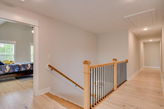 hall with baseboards, attic access, wood finished floors, and an upstairs landing
