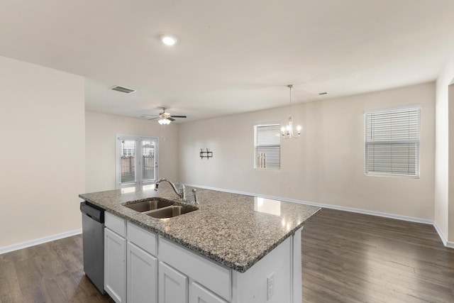 kitchen featuring stainless steel dishwasher, a kitchen island with sink, sink, white cabinets, and hanging light fixtures