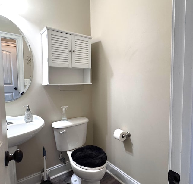 half bathroom with baseboards and toilet