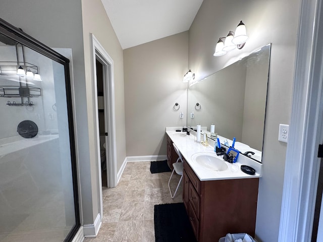 bathroom featuring a shower stall, double vanity, vaulted ceiling, and baseboards