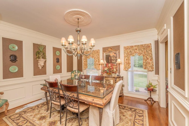 3287 Surrey Rd, Thomson, GA 30824 - dining room featuring wood finished floors, ornamental molding, a decorative wall, and a chandelier