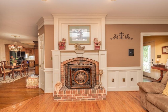 3287 Surrey Rd, Thomson, GA 30824 - living room with wainscoting, a notable chandelier, ornamental molding, and light wood-style flooring