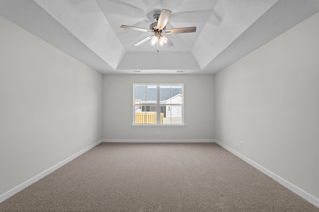 carpeted spare room featuring ceiling fan and a raised ceiling