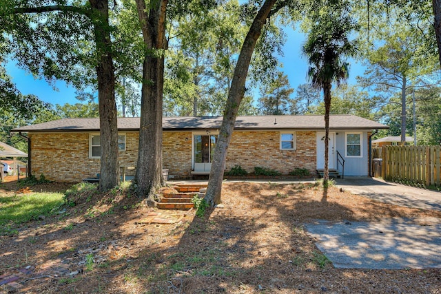 rear view of property with fence, brick siding, and entry steps