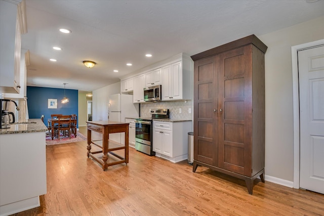 kitchen with stainless steel appliances, a sink, recessed lighting, light wood-type flooring, and white cabinets