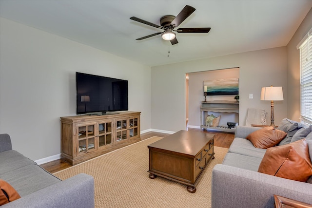living room featuring a ceiling fan, baseboards, and light wood-type flooring