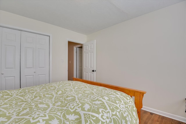 bedroom with wood finished floors, baseboards, and a closet