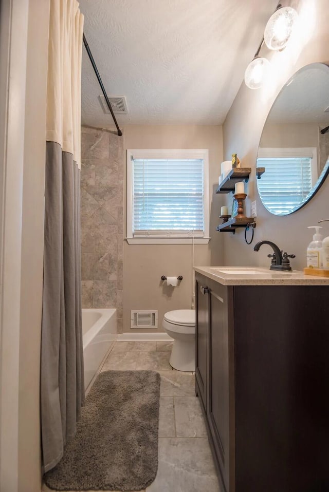 full bath with toilet, vanity, shower / bath combo, a textured ceiling, and tile patterned floors
